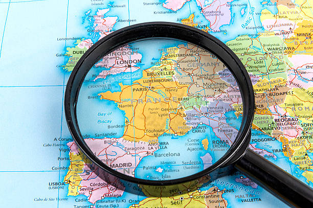 Travel map with magnifying glass, searching city locations. Geography route concept, glass lens focus.