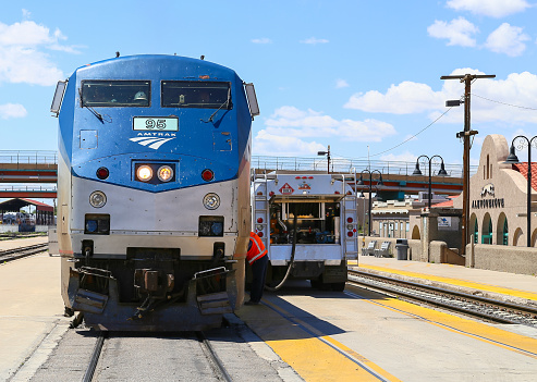 Albuquerque, United States - May 24, 2015: Engine of the Amtrak passenger train Southwest Chief seen from the front at the station. A tanker is parked on the platform next to the train and a worker is fueling the engine.