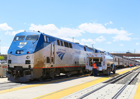Albuquerque, United States - May 24, 2015: The Amtrak passenger train Southwest Chief being fueled at the station. The tanker is parked next to the engine, several passengers are on the platform.