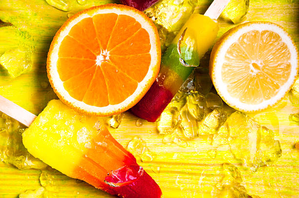Colorful ice lolly and friuts on green wooden background