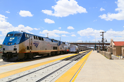 Albuquerque, United States - May 24, 2015: The Amtrak passenger train Southwest Chief at the station. A tanker is parked on the platform next to it, a worker and passengers are around.