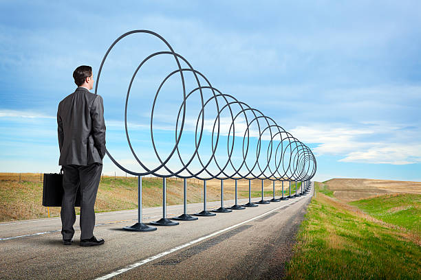 istock Businessman Looking Down Road Lined With Hoops To Jump Through 583994778