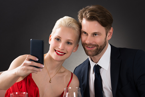 Young Happy Couple Taking Selfie With Their Smartphone In A Restaurant