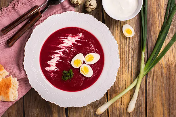Cold beetroot gazpacho soup with quail egg and sour. Top view. Rustic style