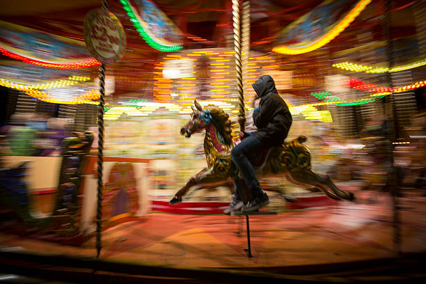 Merry-go-round in London, England London, England, United Kingdom - November 2, 2013: Panning shot of a teenager or young man riding a merry-go-round horse at night in London, England carousel photos stock pictures, royalty-free photos & images