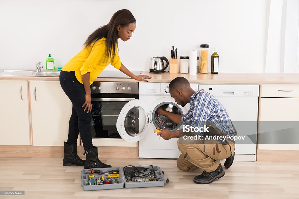 Technician Repairing Washing Machine Young African American Technician Repairing Washing Machine In Kitchen Repairing Stock Photo