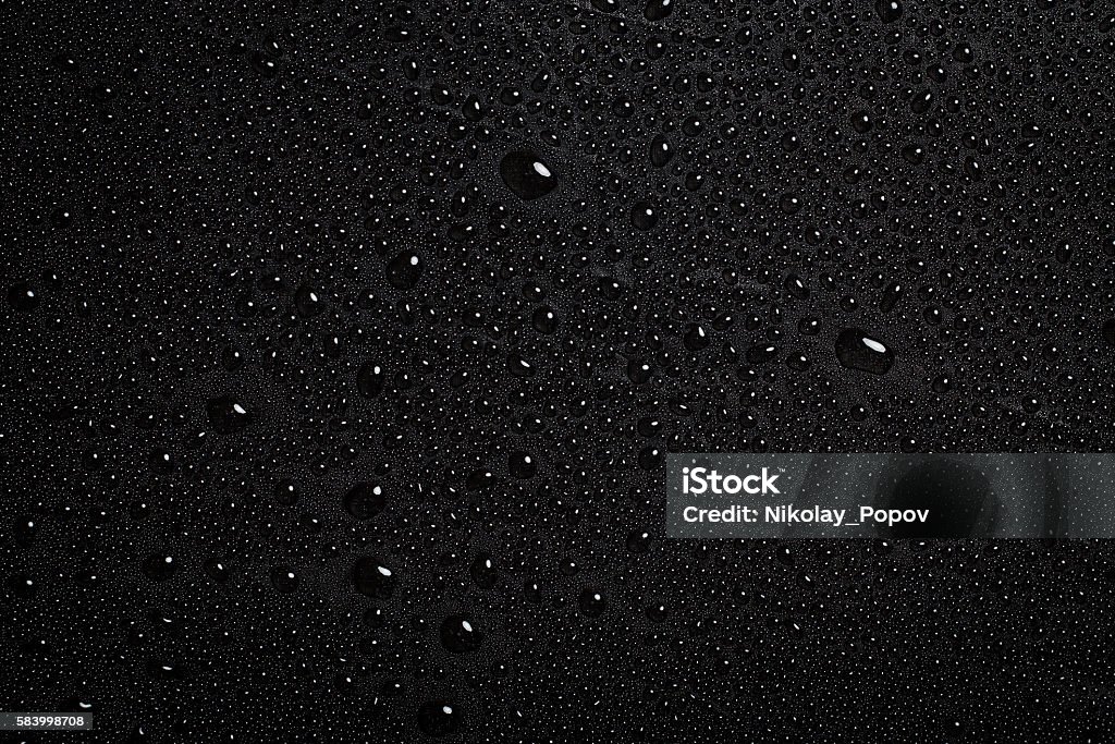 Drops of water. Drops of water on a dark matte surface close up. Black Color Stock Photo