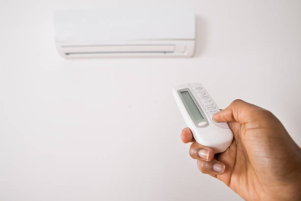 istock Person's Hand Holding Remote To Operate Air Conditioner 584003206
