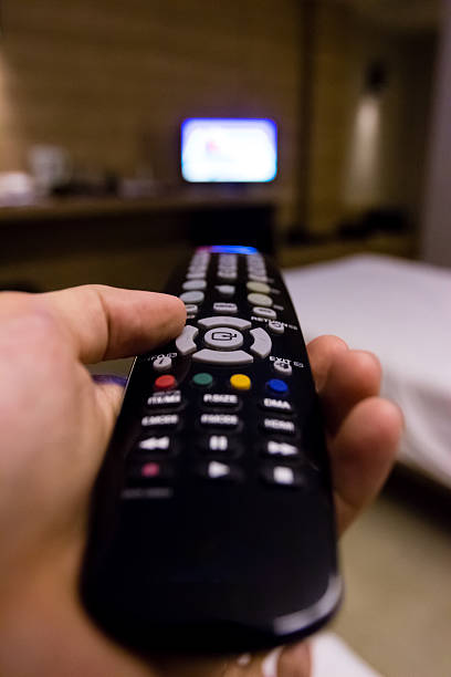 istock Hand holding black remote television with blurry background 584003622
