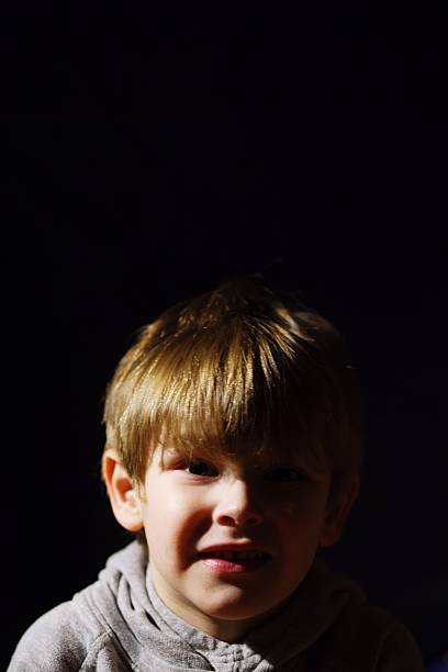 istock Portrait Of Smiling Boy Against Black Background 584185461