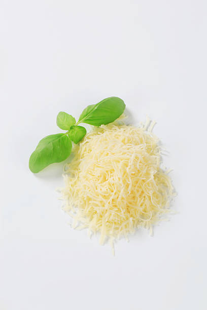 pile of grated cheese with basil on white background