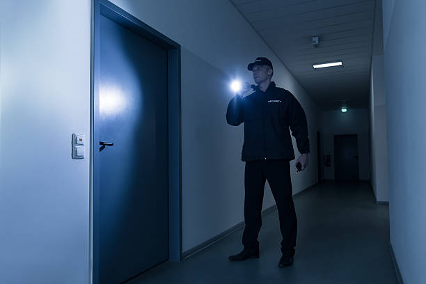 istock Security Guard With Flashlight Standing In Front Of Door 584207970