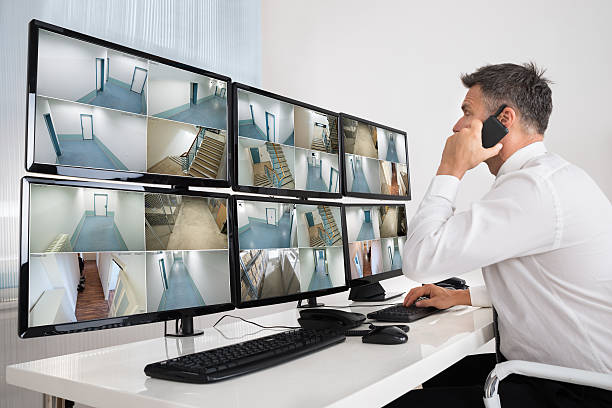 Security System Operator Looking At CCTV Footage Side view of security system operator using walkie-talkie while looking at CCTV footage security guard photos stock pictures, royalty-free photos & images