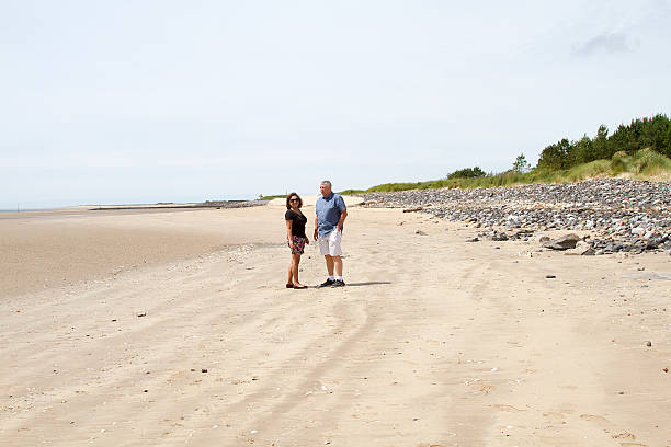 istock Couple standing in the distance on a beach 584210160