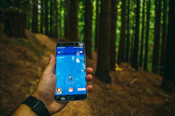 Cabezón de la Sal, Spain - July 29, 2016: A hand holding a mobile phone in a forest, with the popular Pokemon Go game displayed on its screen.