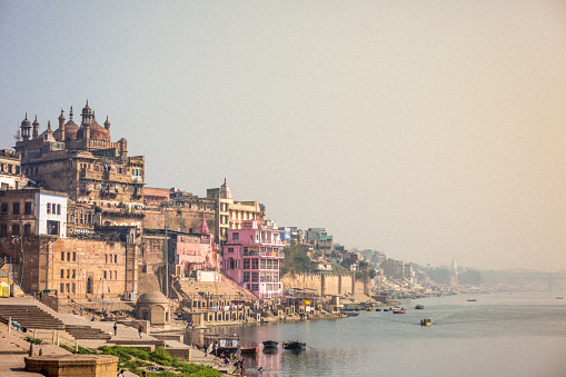 Cityscape of Varanasi where buildings on the ghats and people bathing in the Ganges are visible.