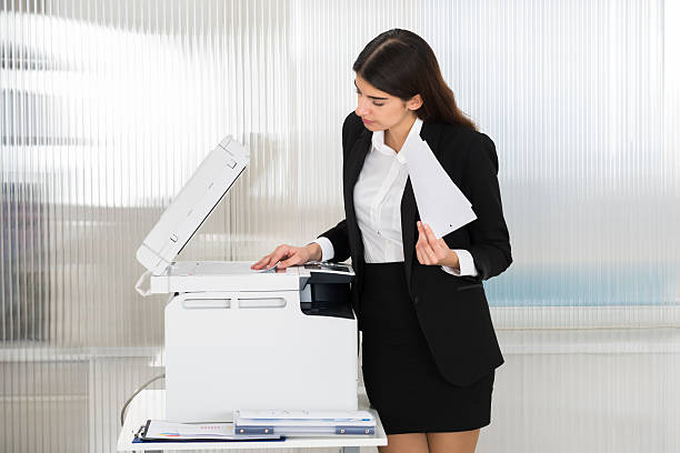 istock Businesswoman Using Photocopy Machine In Office 584211574