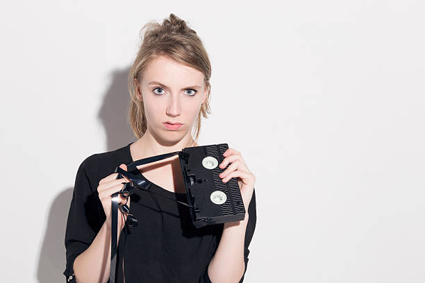 istock Young woman damaging a vhs tape. 584217766