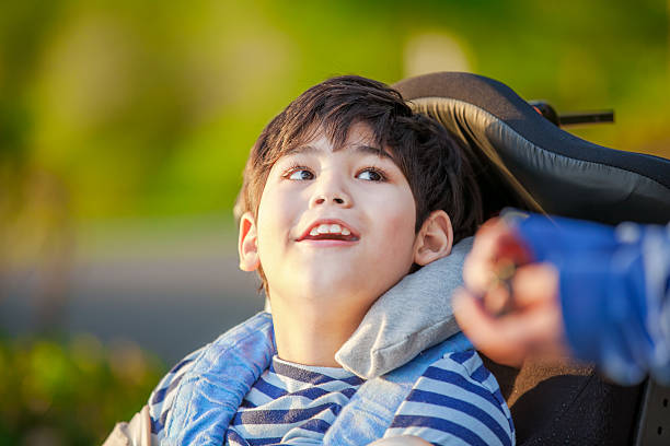 Young disabled boy in wheelchair looking up into sky stock photo