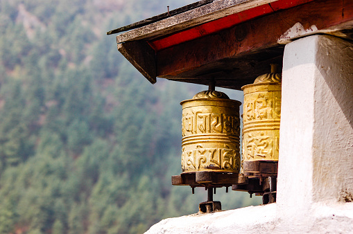 The sunshine is on the brass prayer wheels under the wooden roof in a village on the Everest base camp trekking route in Himalayas.