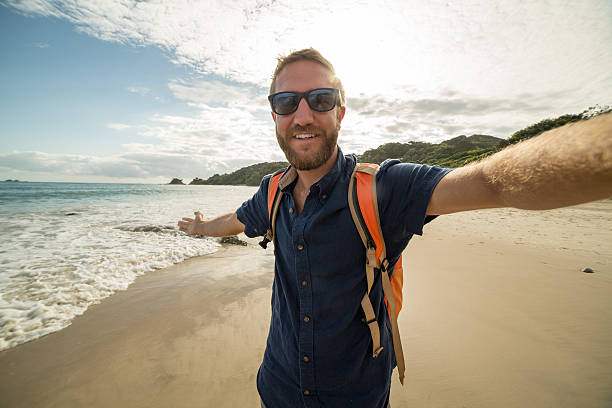 giovane in spiaggia scatta selfie ritratto usando action camera - australia photographing camera beach foto e immagini stock