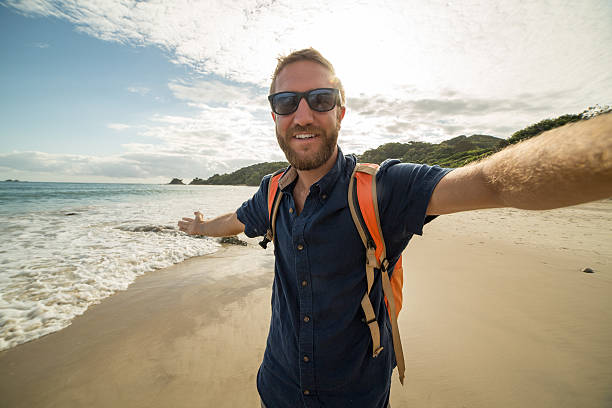 istock Young man on beach takes selfie portrait using action camera 584222218