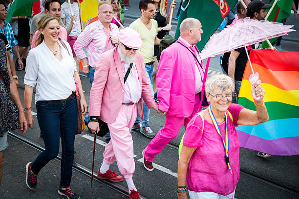 old men holding hand at Pride Walk, Amsterdam Gay EuroPride Amsterdam, the Netherlands - July 23, 2016: 2 old men holding hand at Pride Walk, demonstration parade from Vondelpark to Dam Square during Pink Saturday Gay Euro Pride celebrations man showing peace sign stock pictures, royalty-free photos & images