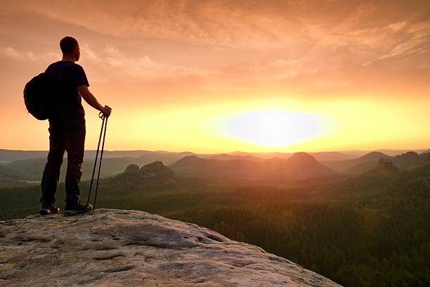 istock Man with poles in hand and sporty backpack above valley. 584226498