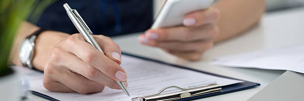istock Woman writing something and looking at mobile phone 584227302
