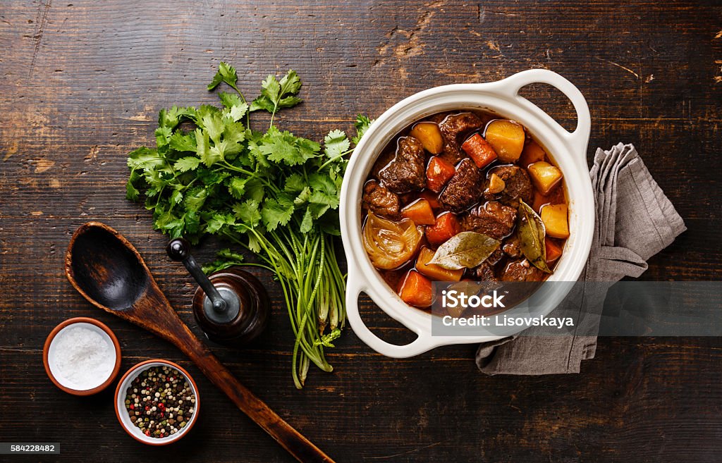 Beef meat stewed with potatoes in pot Beef meat stewed with potatoes, carrots and spices in ceramic pot Stew Stock Photo