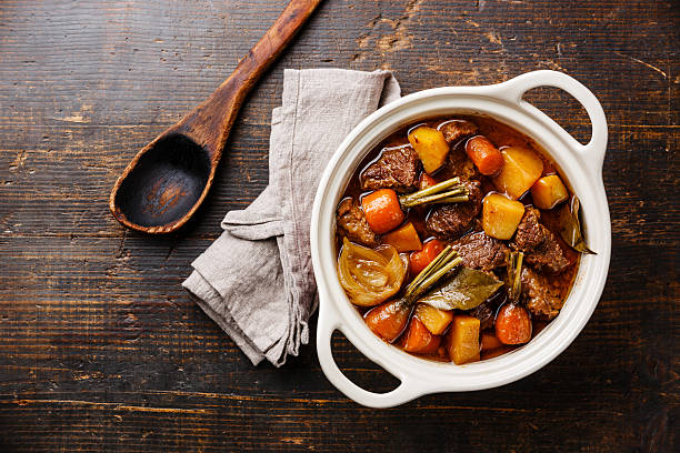 Beef meat stewed with vegetables Beef meat stewed with potatoes, carrots and spices in ceramic pot on wooden background beef stew stock pictures, royalty-free photos & images