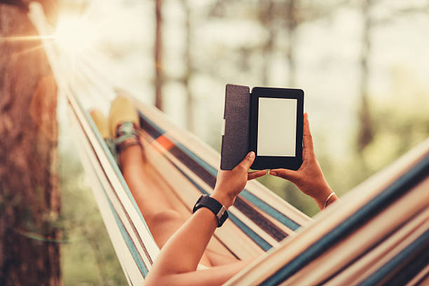 istock Young girl in a hammock with e-book 584229408