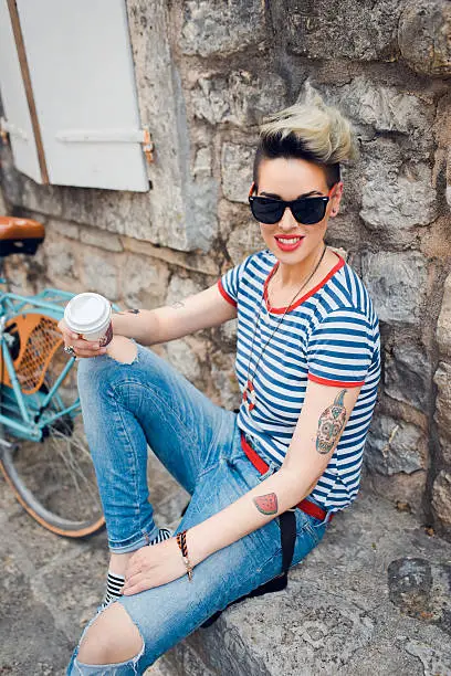 A gorgeous young woman enjoying some coffee while resting near her bicycle