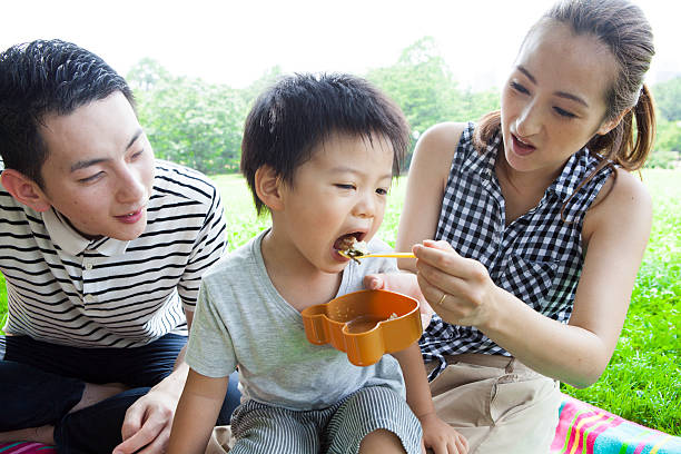 mütter essen ein mittagessen für kinder im park - child portrait fine art portrait multi colored stock-fotos und bilder