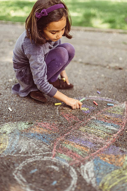 istock Kid drawing with chalk on asphalt 584230790