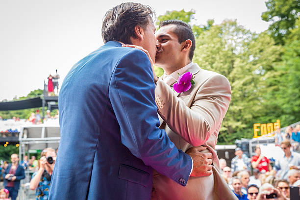 Gay wedding ceremony during Pink Saturday Gay EuroPride Amsterdam, the Netherlands – July 23, 2016: gay wedding ceremony of Lucien Spee, director from Amsterdam Gay Pride association, and Victor at Vondelpark during Pink Saturday Gay Euro Pride celebrations gay wedding kiss stock pictures, royalty-free photos & images