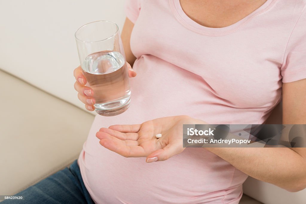 Pregnant Woman Hand With Glass Of Water And Vitamin Pill Close-up Of Pregnant Woman Hand With Glass Of Water And Vitamin Pill Pregnant Stock Photo