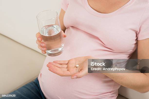 Pregnant Woman Hand With Glass Of Water And Vitamin Pill Stock Photo - Download Image Now