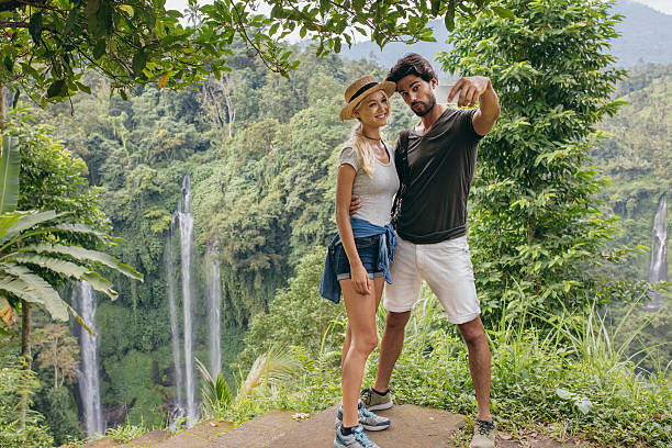 istock Beautiful couple together on cliff taking selfie with waterfall 584232680