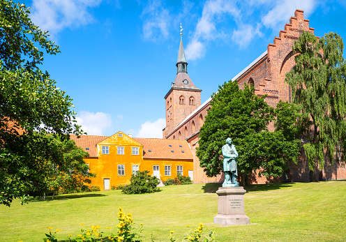 Odense, the gothic St. Canute's Cathedral with the Hans Christian Andersen monument in the foreground