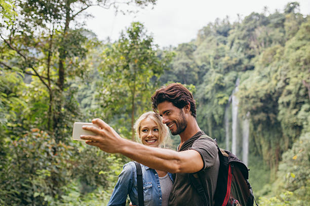 istock Couple taking picture in front of waterfall 584232884