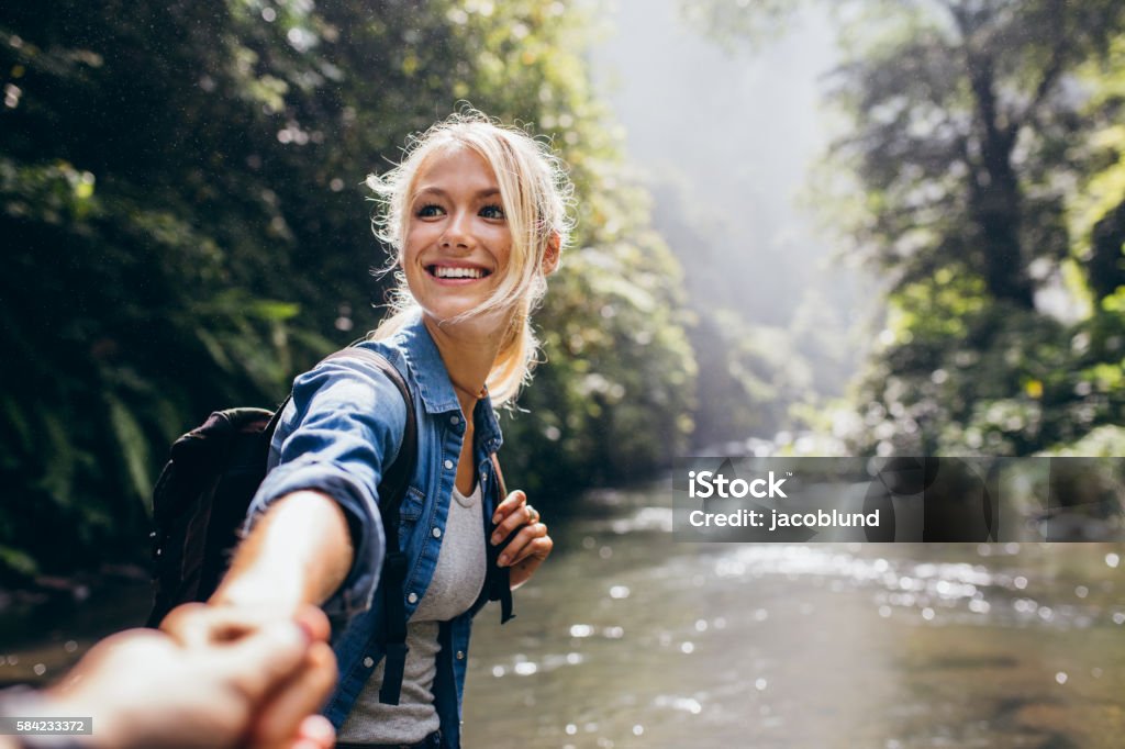 Hiker woman holding man's hand on a nature hike Hiker woman holding man's hand and leading him on nature outdoor. Couple in love. Point of view shot. Hiking Stock Photo