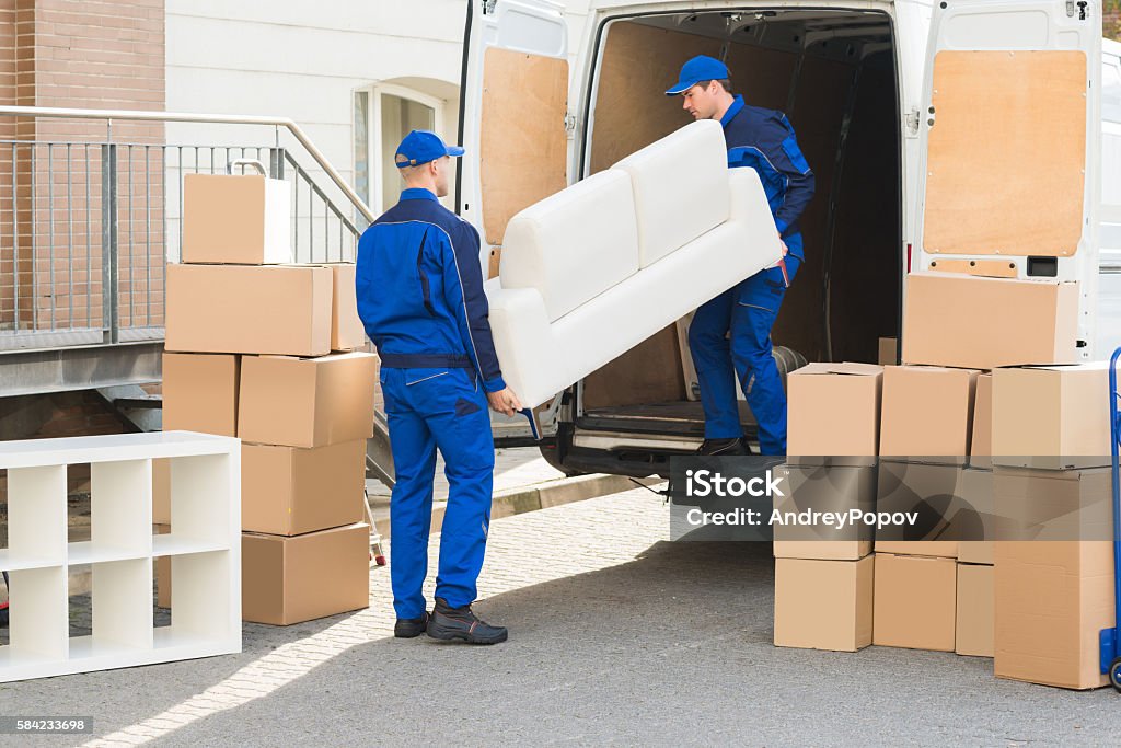 Movers Unloading Sofa From Truck Young male movers unloading sofa from truck on street Moving House Stock Photo