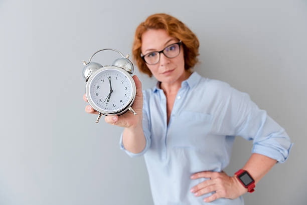 istock Pleasant serious woman holding alarm clock 584235374