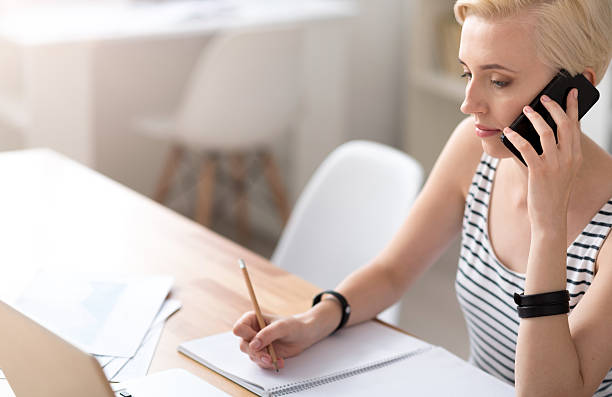 istock Woman taking notes and talking on smartphone 584242086