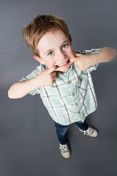 istock smiling young child standing with big mouth for comical misbehavior 584244540