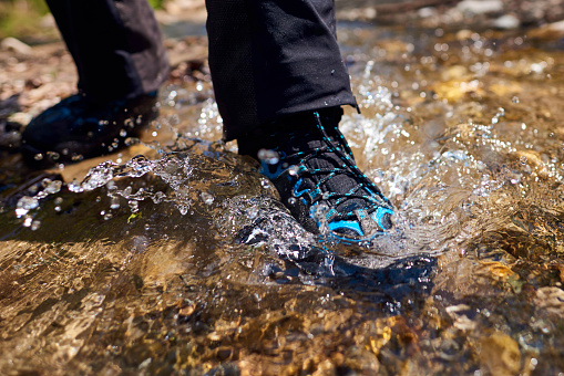unrecognizable hiker woman legs in the water, waterproof shoes.