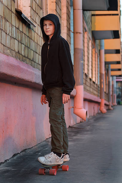 Adolescente che fa skateboard su City Street al tramonto - foto stock