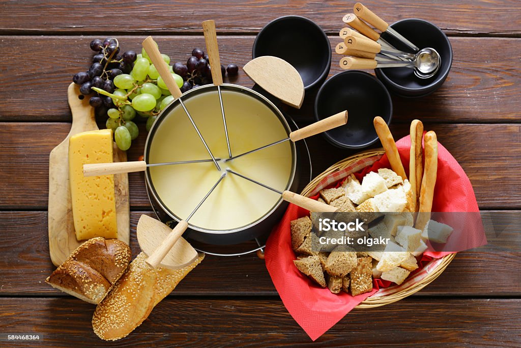 Traditional set of utensils for fondue, with bread, cheese, grapes Fondue Stock Photo