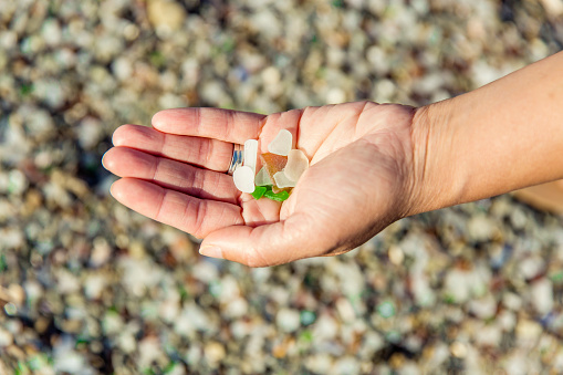 Stock photo of a hand holding a handfull of glass washed up on a beach.